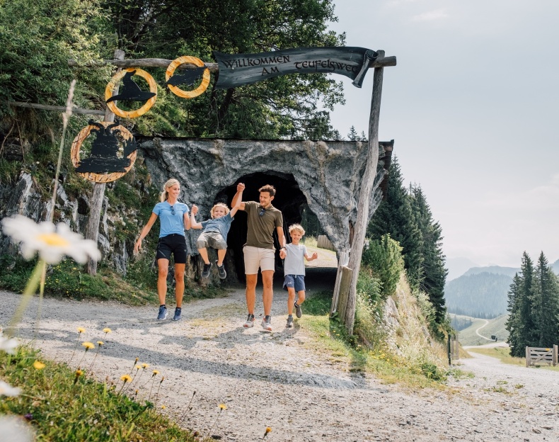 Familie sitzt am Poolrand und spielt mit den F&uuml;&szlig;en im Wasser auf der Terasse des Reslresorts