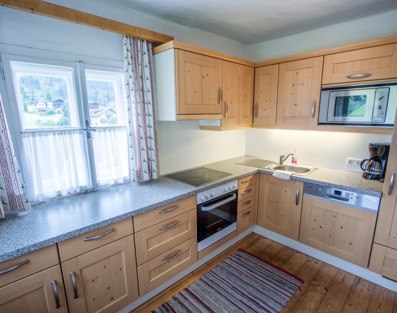 Helle Küche mit Holzmöbeln, modernen Geräten und Fenster mit Ausblick, ausgestattet mit Spülmaschine