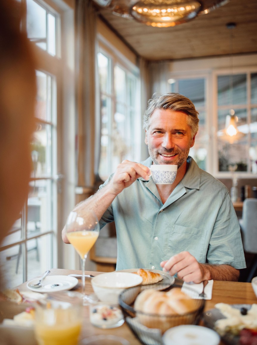 Mann sitzt am Frühstückstisch und trinkt Kaffee