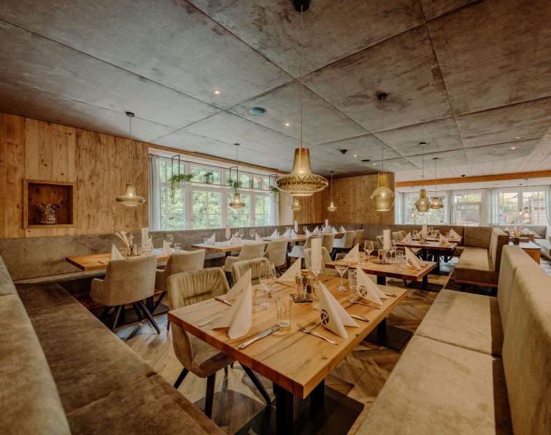 Stilvoll eingerichtetes Restaurant mit Holzdekor und gedeckten Tischen im Resl Resort