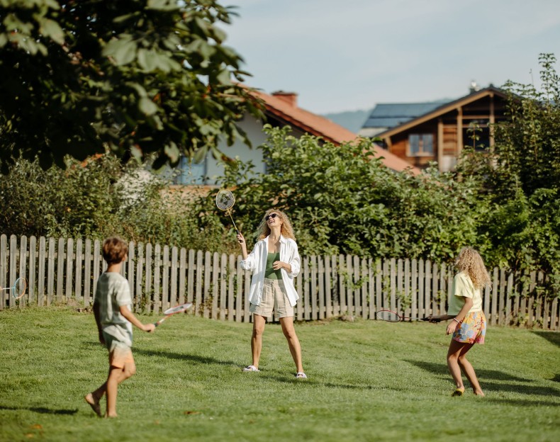Familie spielt Badminton im Garten und genießt den Urlaub im Familienhotel Resl im Salzburger Land