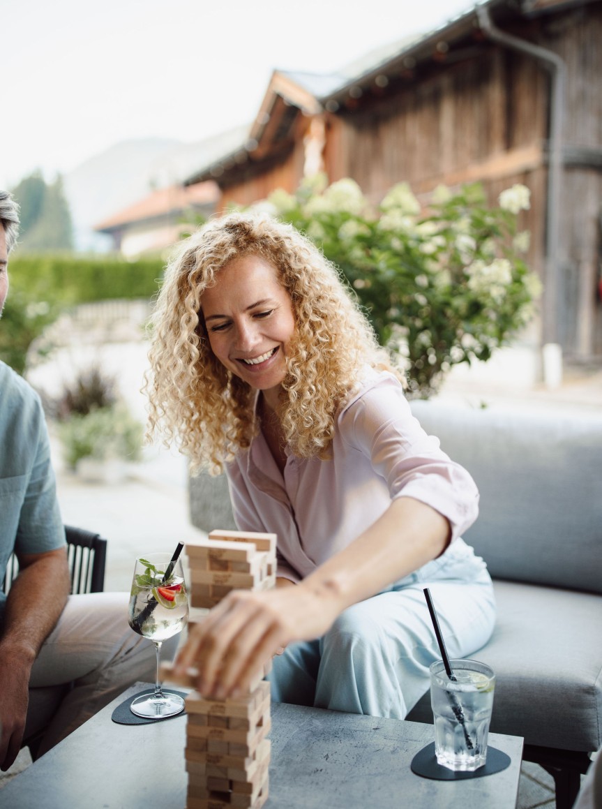 Frau spielt mit ihrer Familie Jenga auf der Resl Terrasse