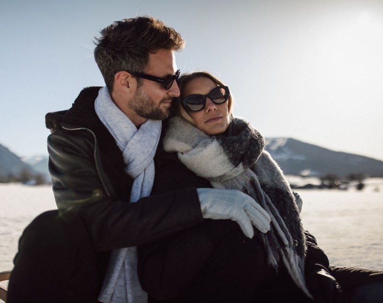 Paar umgeben von verschneiten Bergen im Winterurlaub in Flachau