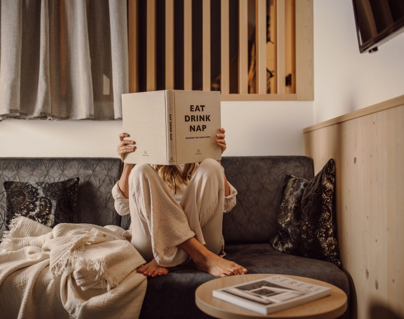 Dame liest ein Buch in ihrem gemütlichen Zimmer im Hotel Resl