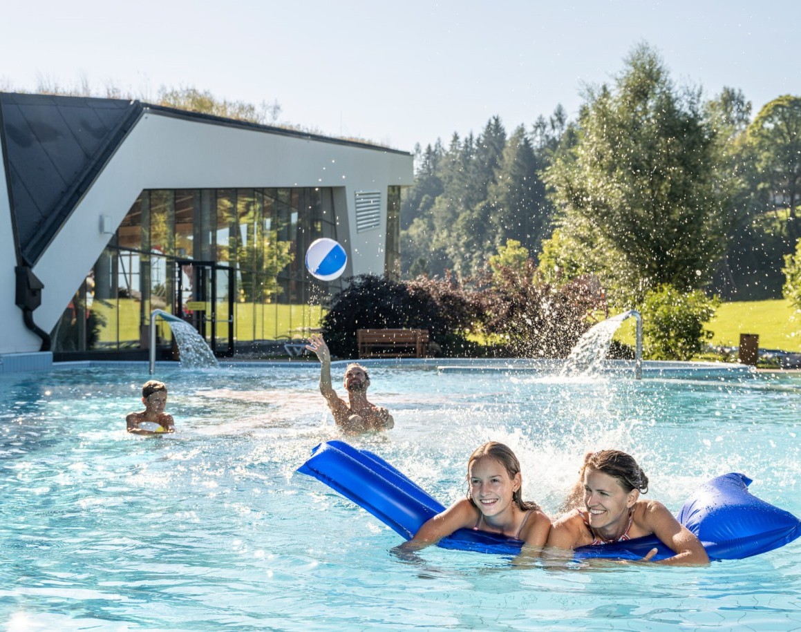 Familie im Außenpool mit einem Wasserball