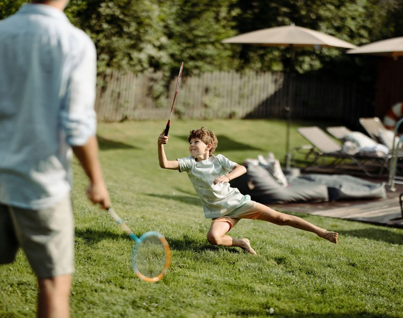 Ein Junge spielt Federball mit seinem Vater im Urlaub in Flachau