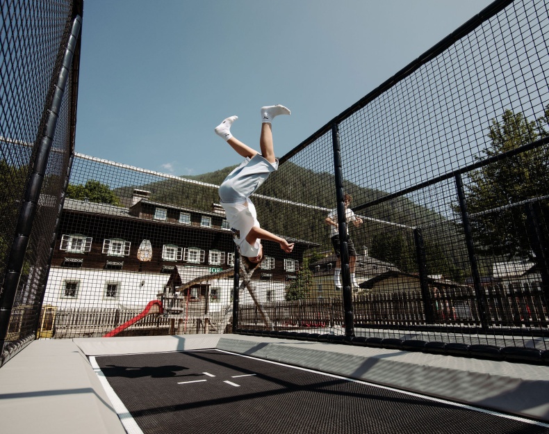 Kinder springen auf einem gesicherten Outdoor-Trampolin im Familienhotel Resl in Flachau