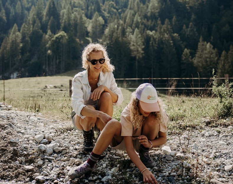 Eine Frau und ein Kind sitzen auf einem steinigen Pfad in einem Waldgebiet