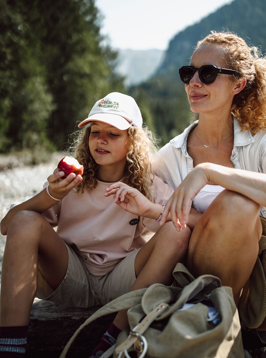 Mädchen und Frau sitzen draußen, Mädchen genießt einen Apfel