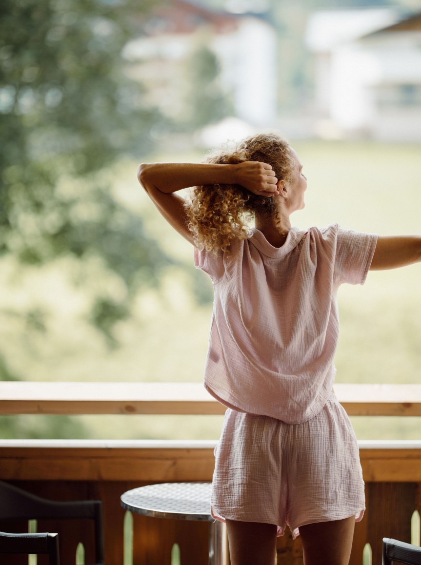 Dame auf dem Balkon ihres Zimmers im Resl Resort mit Ausblick auf die wunderschöne Umgebung