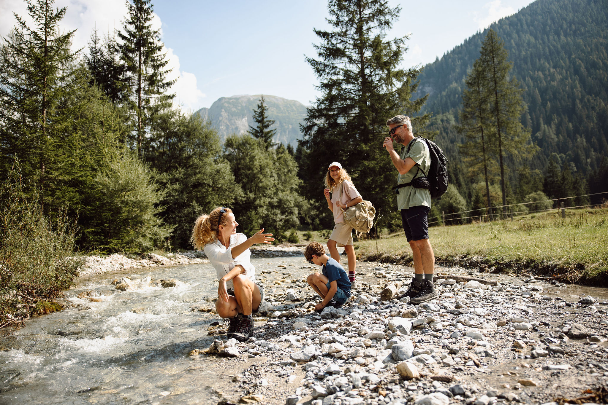 Eine Familie macht eine Wanderung entlang des Flusses in den Bergen