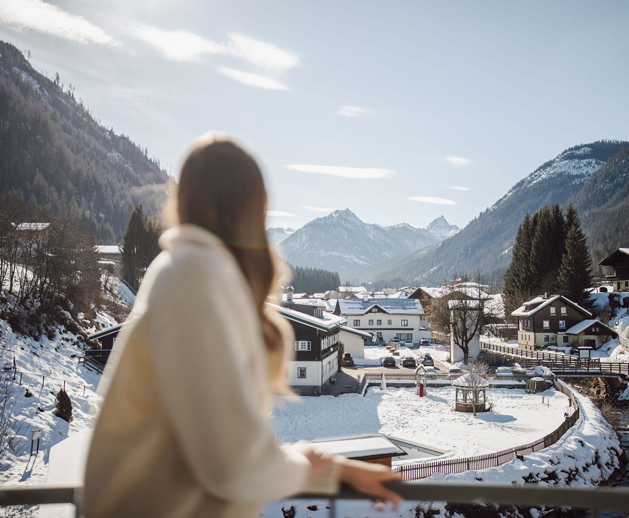 Frau genießt den Bergblick vom Balkon im Reslwirt Flachau im Winter
