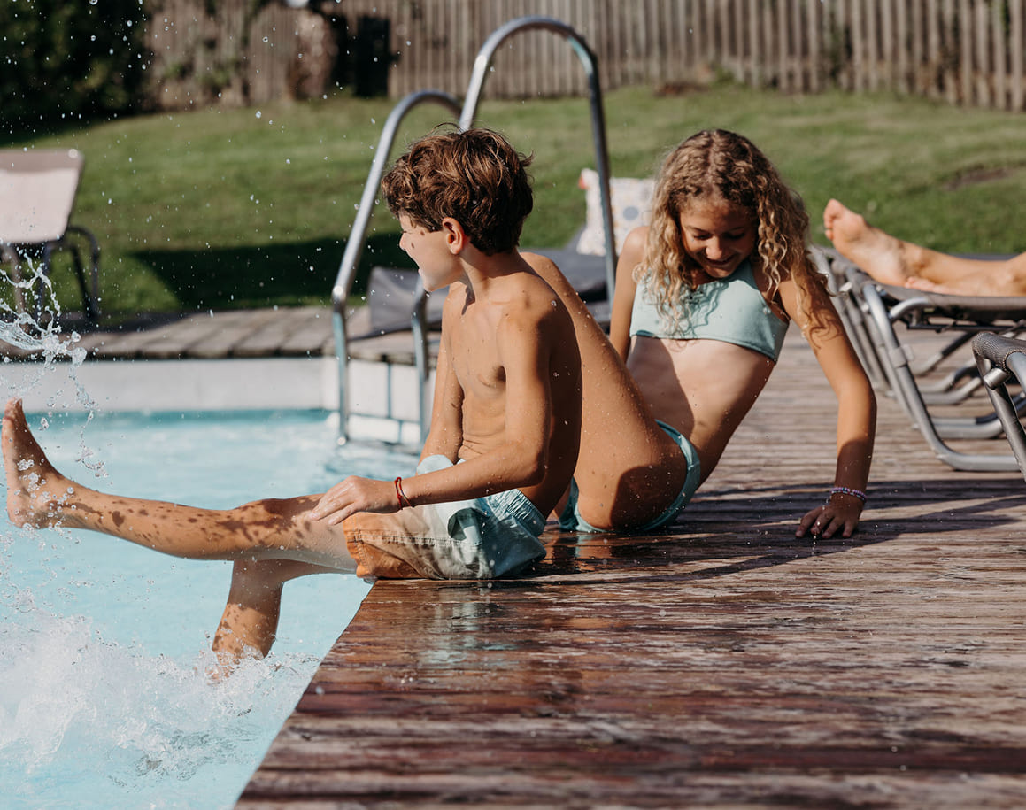 Kinder planschen am Rand eines Pools im Freien