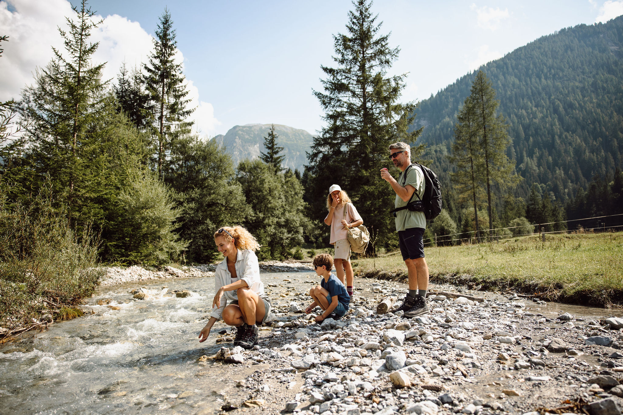Eine Familie erkundet einen Bach in einer bergigen Waldlandschaft