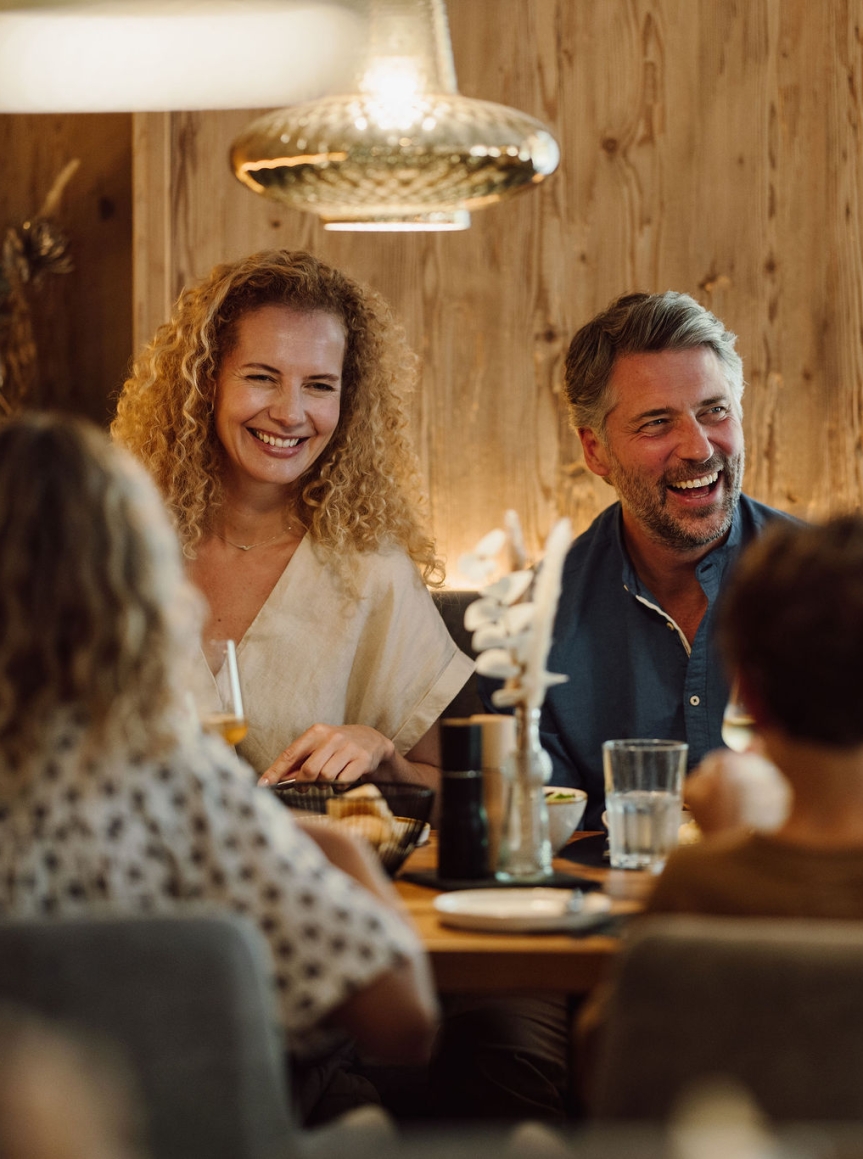 Eine Familie sitzt lächelnd am Tisch im gemütlichen Restaurant des Hotel Resl