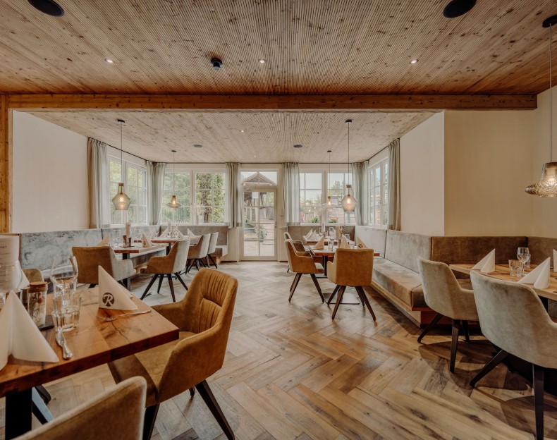 Ein elegantes Restaurant mit Holzdecke und großen Fenstern, das aufgeräumt und einladend wirkt