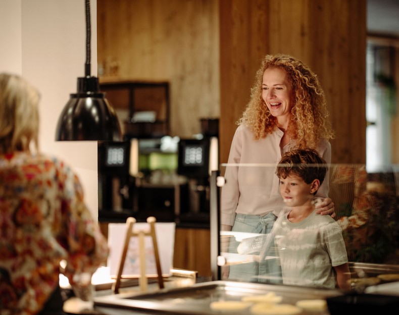Eine Frau und ein Junge lächeln am Buffet der Hotel Resl in Flachau