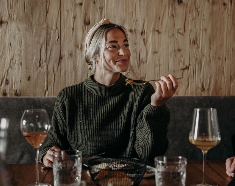 Paar genie&szlig;t das Essen im Restaurant 1774 in Flachau und st&ouml;&szlig;t mit Rotweingl&auml;sern an