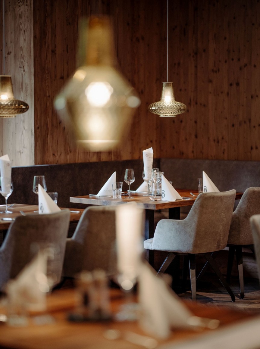 Gemütliches Ambiente mit eingedeckten Holztischen und hängenden Lampen