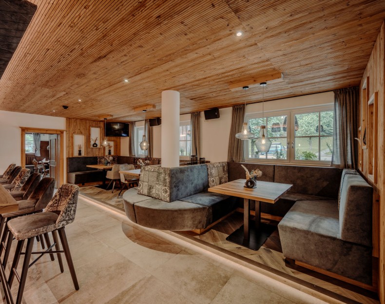 Gemütlicher Restaurantbereich mit Holzakzenten, Polstersitzen und modernen Lampen