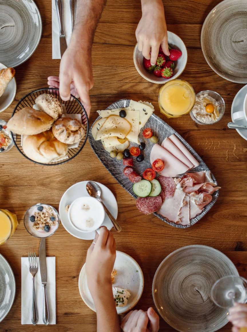Frühstückstisch mit Brötchen, Aufschnitt, Früchten und Getränken, von oben fotografiert