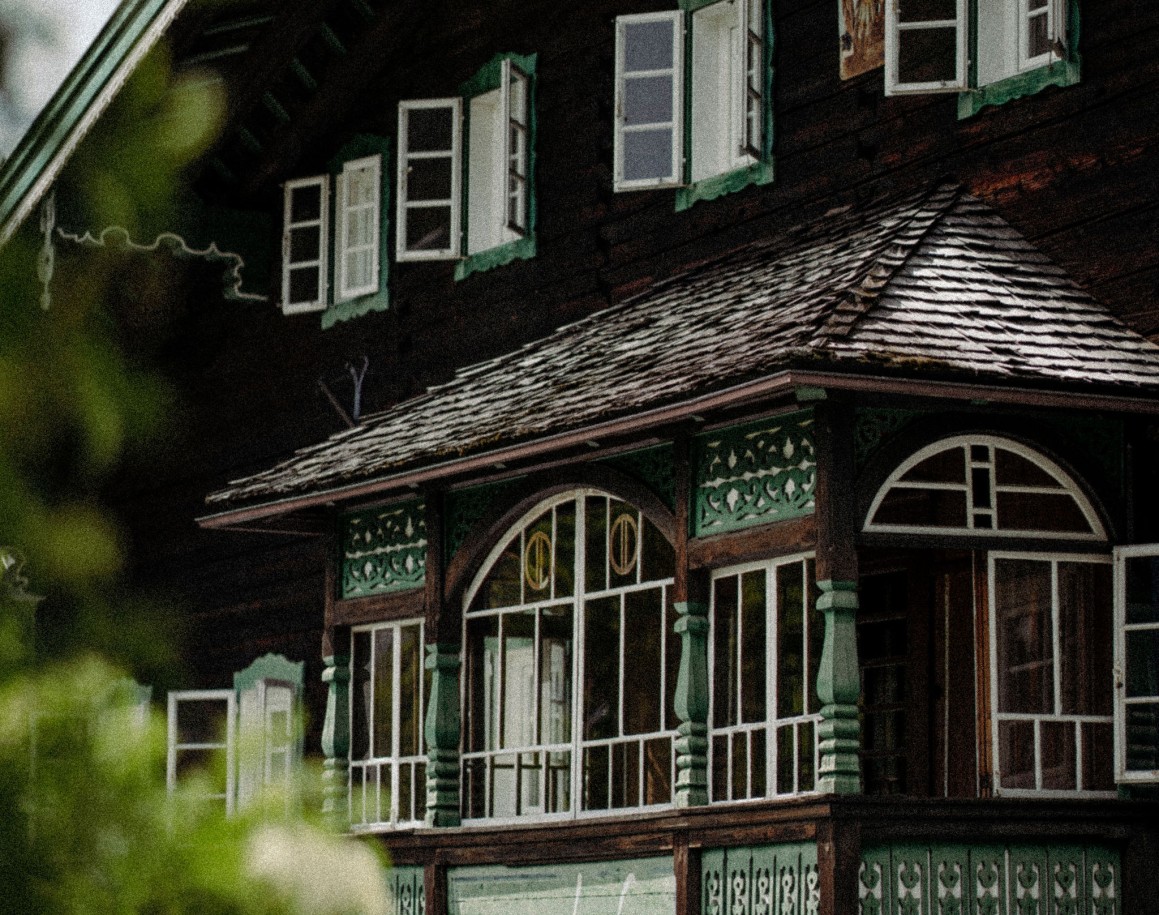 Holzhaus mit bunten Fenstern und geschnitzten Verzierungen - Ennshof