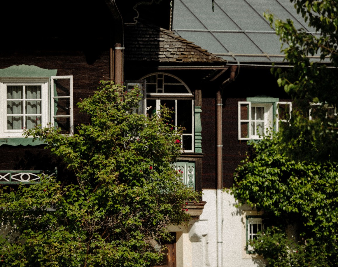 Fassadendetail eines alpinen Hauses mit Holzverkleidung und grünen Fensterläden - Ennshof 1637