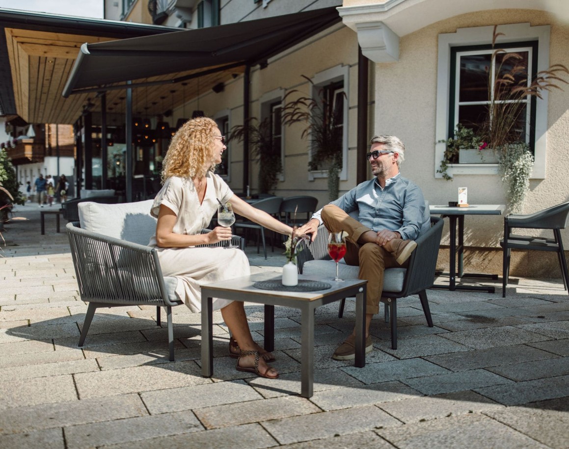 Ein Paar genießt Getränke auf der Resl Terrasse bei Sonnenschein
