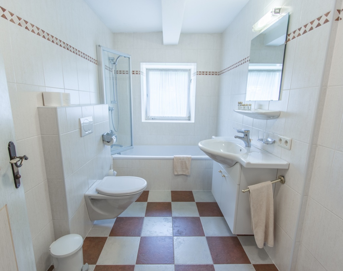 Helles Badezimmer mit Badewanne, Waschbecken und WC, gefliest mit Schachbrettmuster