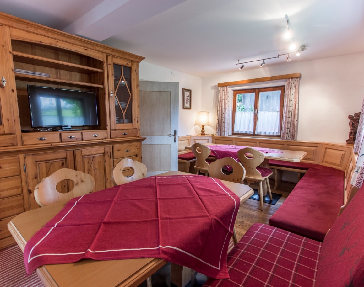 Gemütlicher Essbereich mit Holzmöbeln und roten Tischdecken in einer Stube