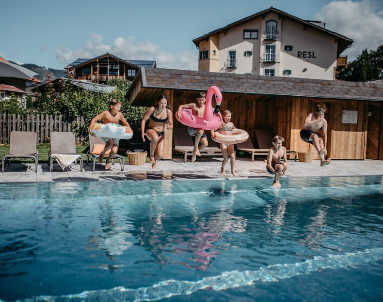 Kinder springen auf einer gesicherten Outdoor-Trampolinanlage im Hotelgarten Resl