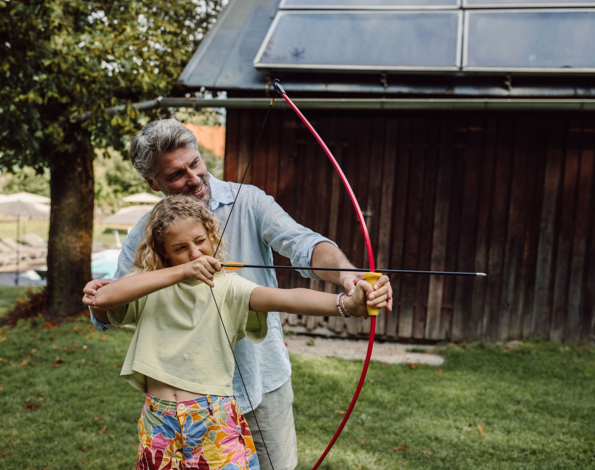 Kind übt Bogenschießen im Garten des Familienhotels
