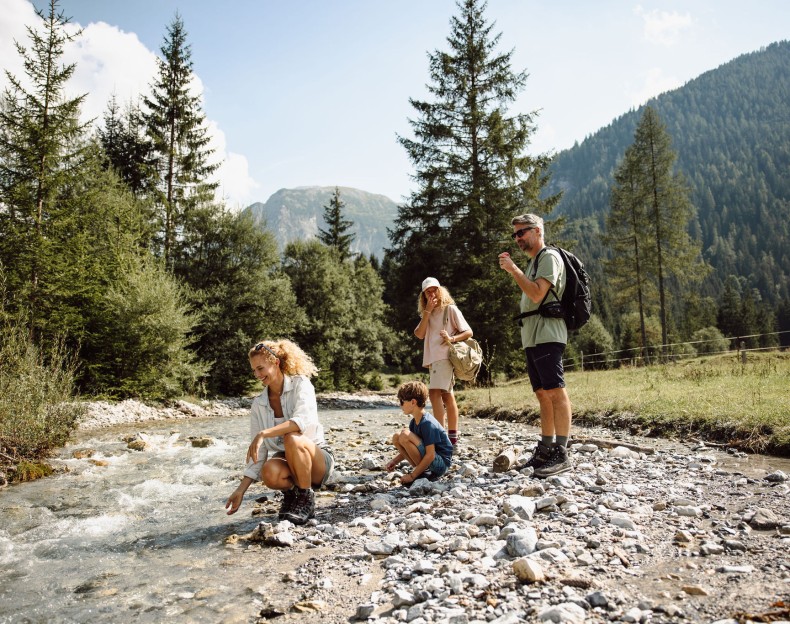 Familie wandert an einem Fluss in den Bergen, während sie die Natur genießt