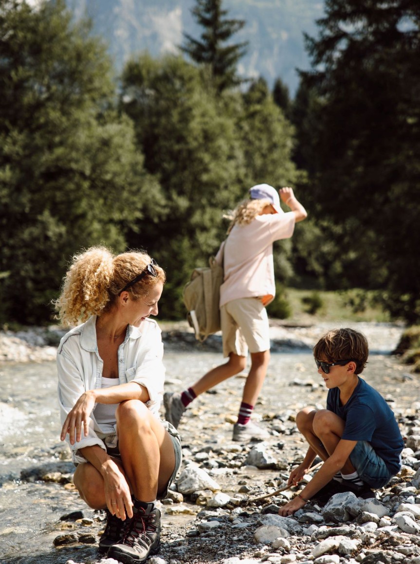 Familie spielt in einem steinigen Bachbett im Wald