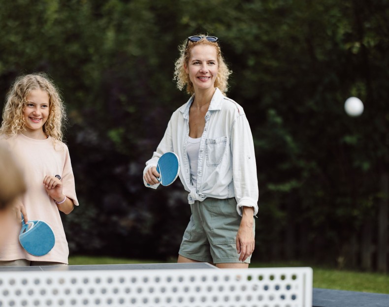 Eine Frau und ein Mädchen spielen Tischtennis im Freien