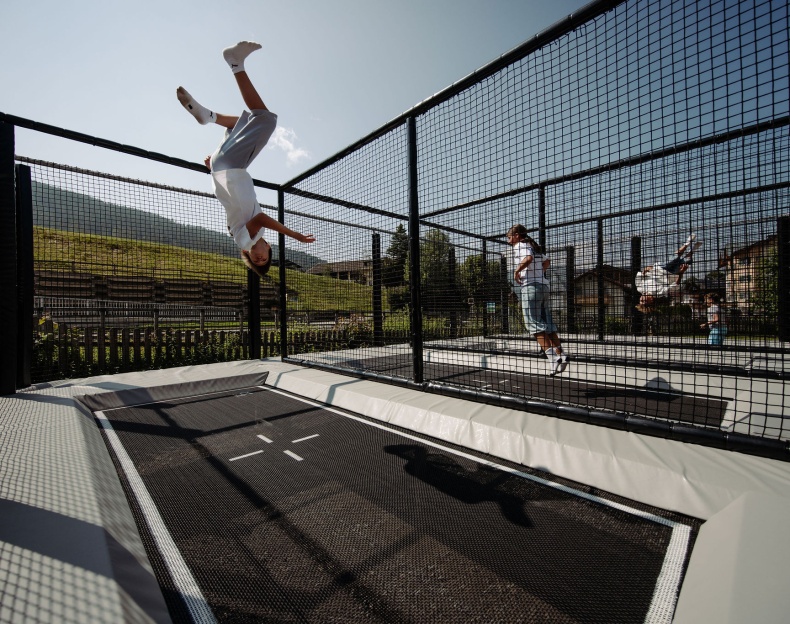 Kinder springen auf einer gesicherten Outdoor-Trampolinanlage im Hotelgarten Resl