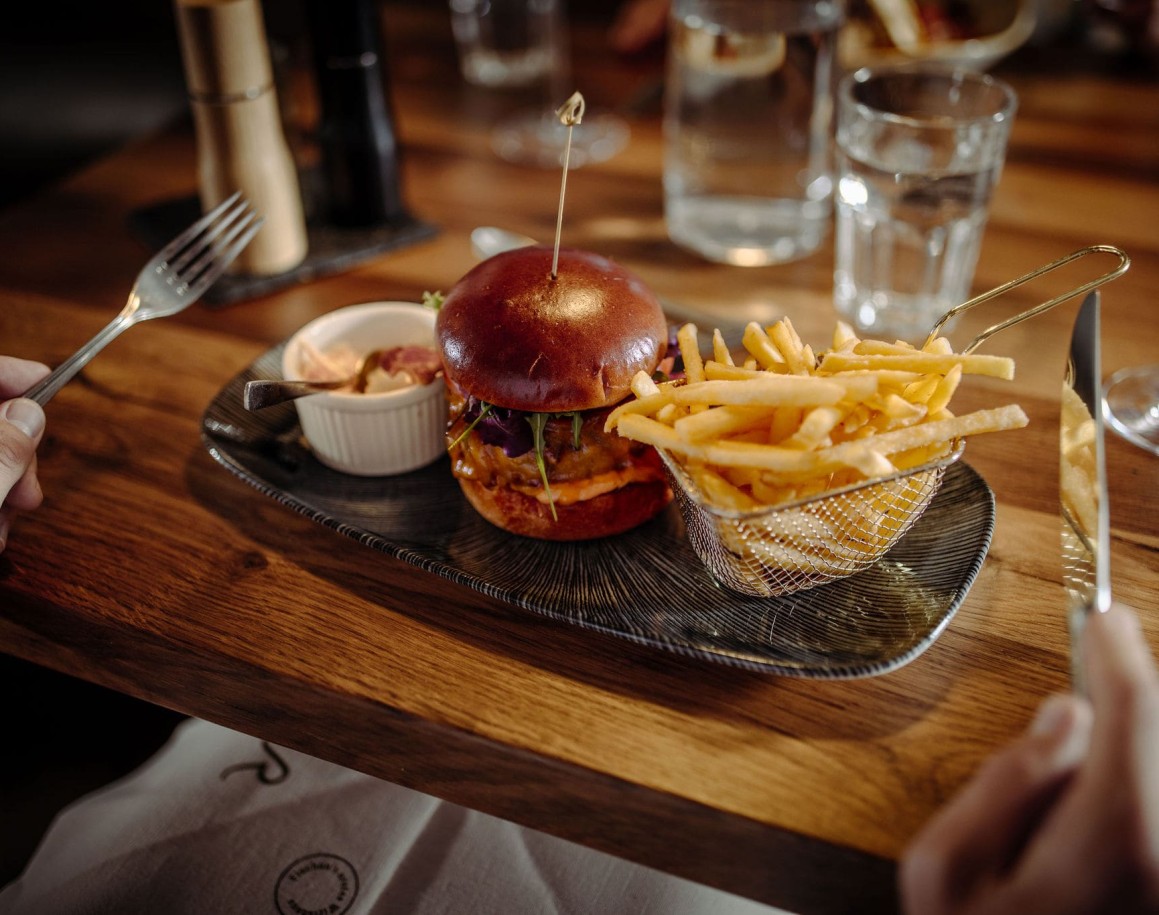 Burger mit Pommes auf schwarzem Teller serviert