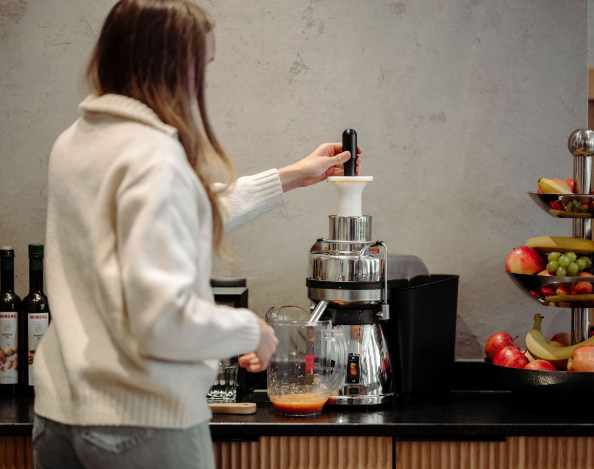 Dame bedient Entsafter am Frühstücksbuffet