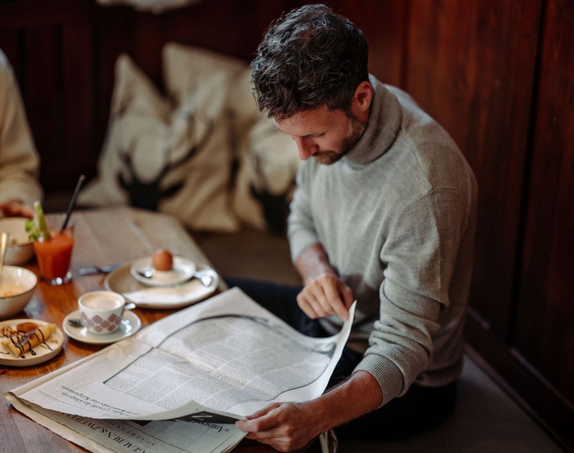 Mann liest Zeitung und genießt sein Frühstück im Hotel Resl