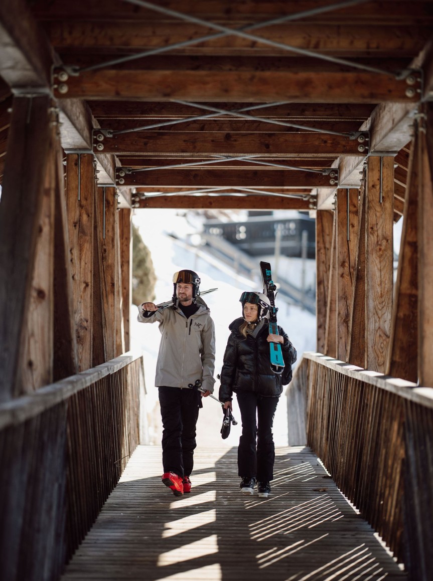 Zwei Wintersportler gehen über eine Holzbrücke beim Skiurlaub in Flachau im Salzburger Land