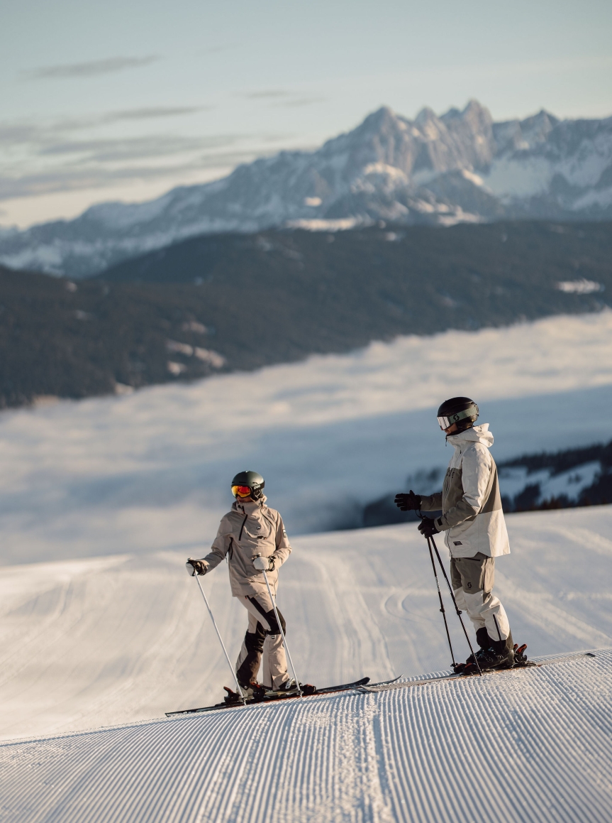 Zwei Wintersportler stehen auf der Piste und schauen auf die Berge rund um Flachau