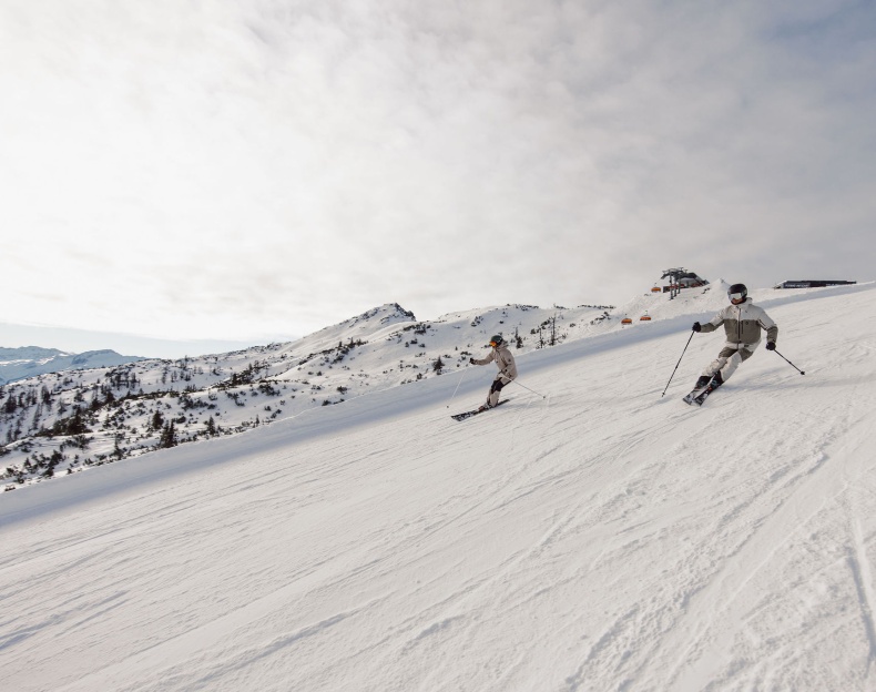 Wintersportler fahren die Piste runter im Winterurlaub in Flachau im Snow Space Salzburg