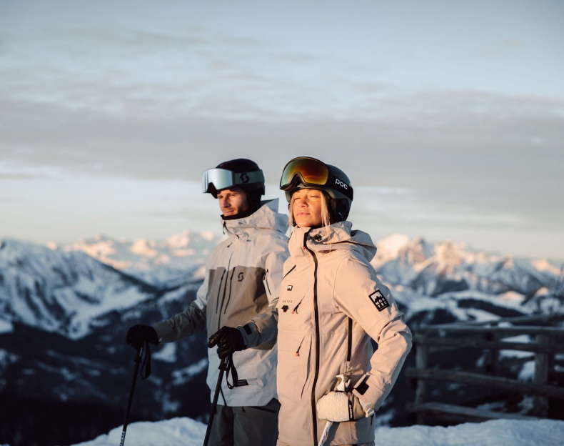 Wintersportler stehen am Berg und lassen sich die Sonne ins Gesicht scheinen