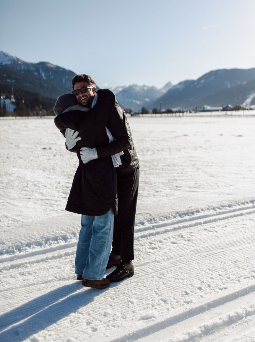 Zwei Personen umarmen sich lächelnd in der verschneiten Salzburger Berglandschaft