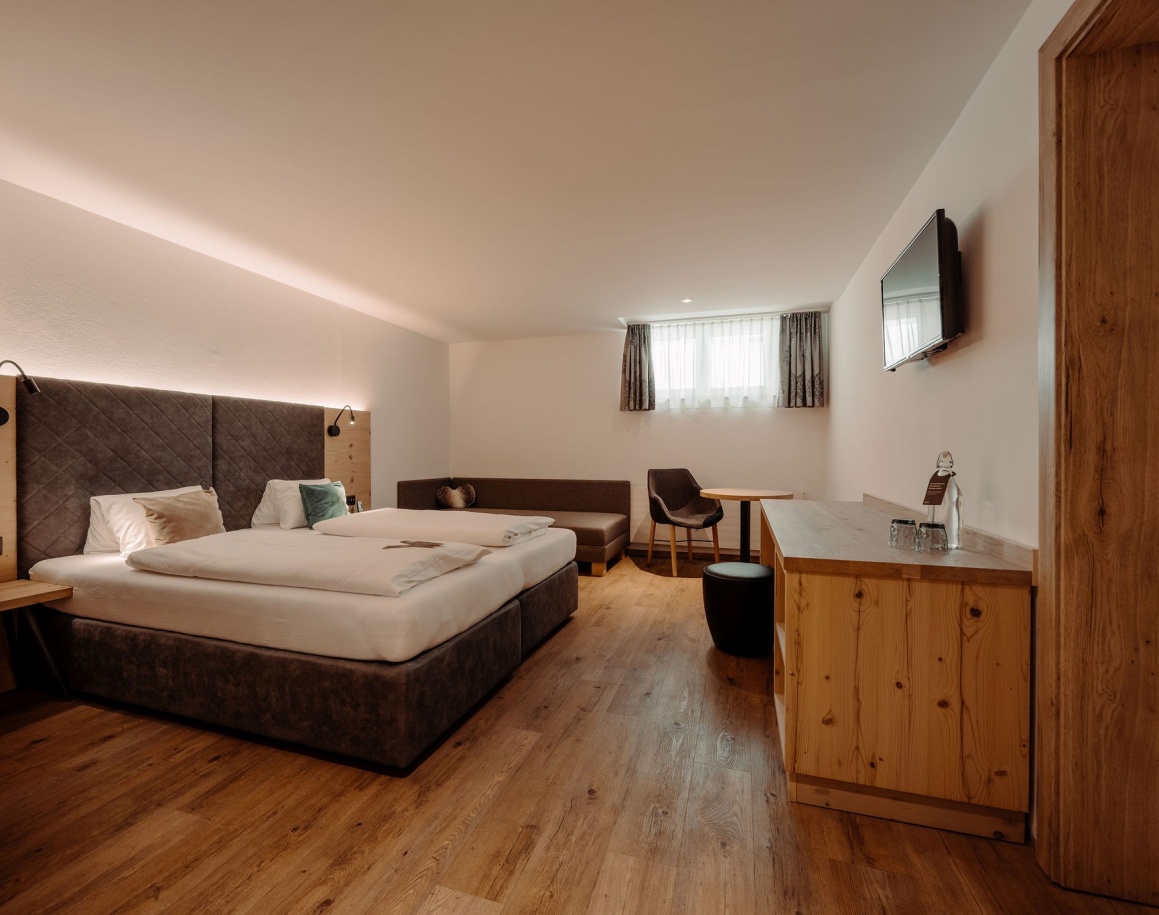 Gemütliches Hotelzimer mit Doppelbett, Holzkommode und Fenster