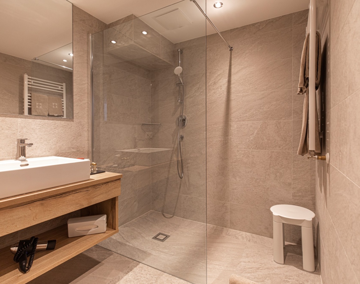 Modernes Badezimer mit großer Dusche und grauen Fliesen