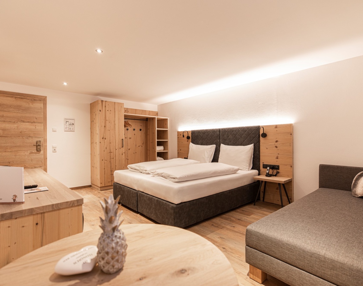 Hotelzimmer mit Doppelbett, Holzelementen und Schreibtisch