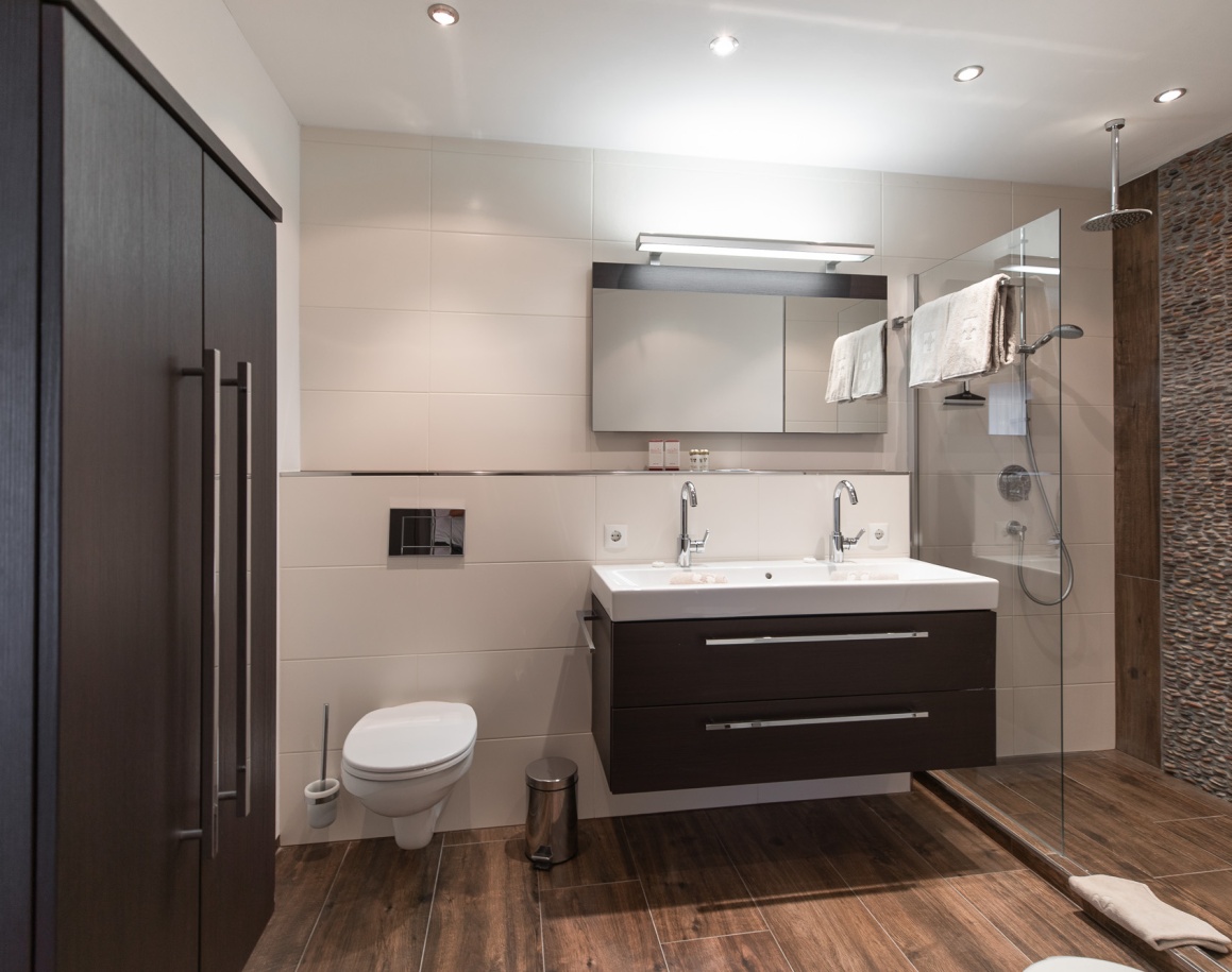 Badezimmer mit Waschbecken, Spiegel und dunklen Fliesenakzenten