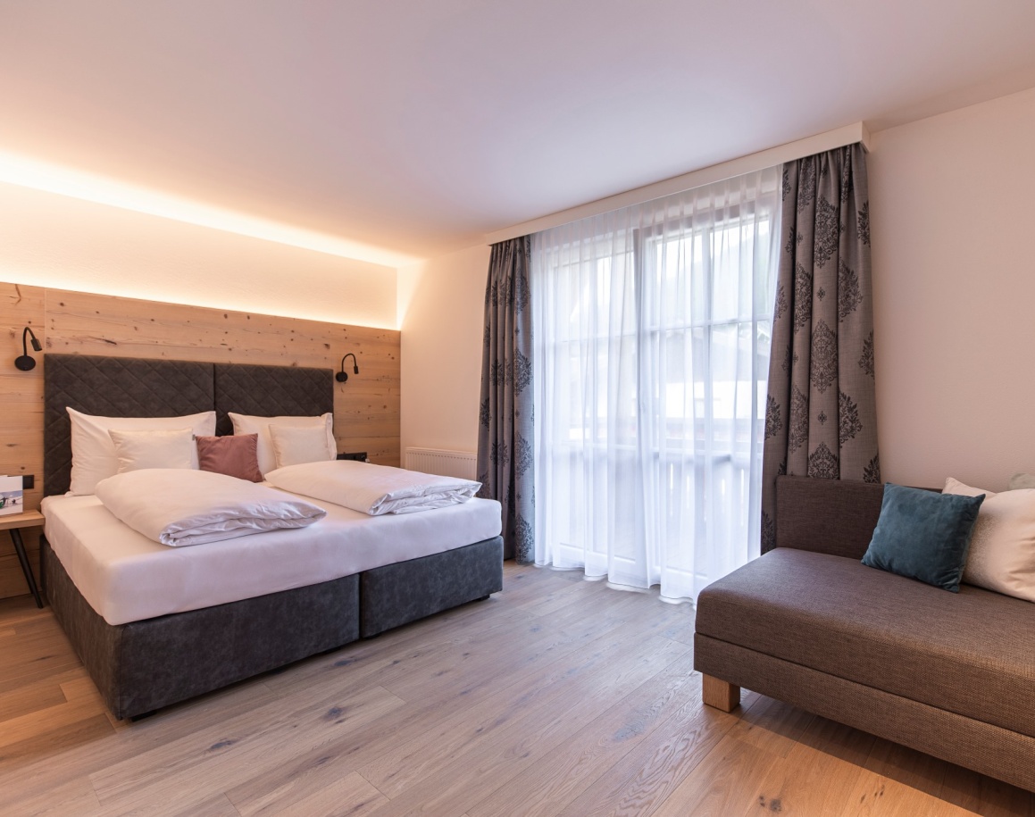 Helles Hotelzimmer mit Doppelbett, Holzelementen und großem Fenster