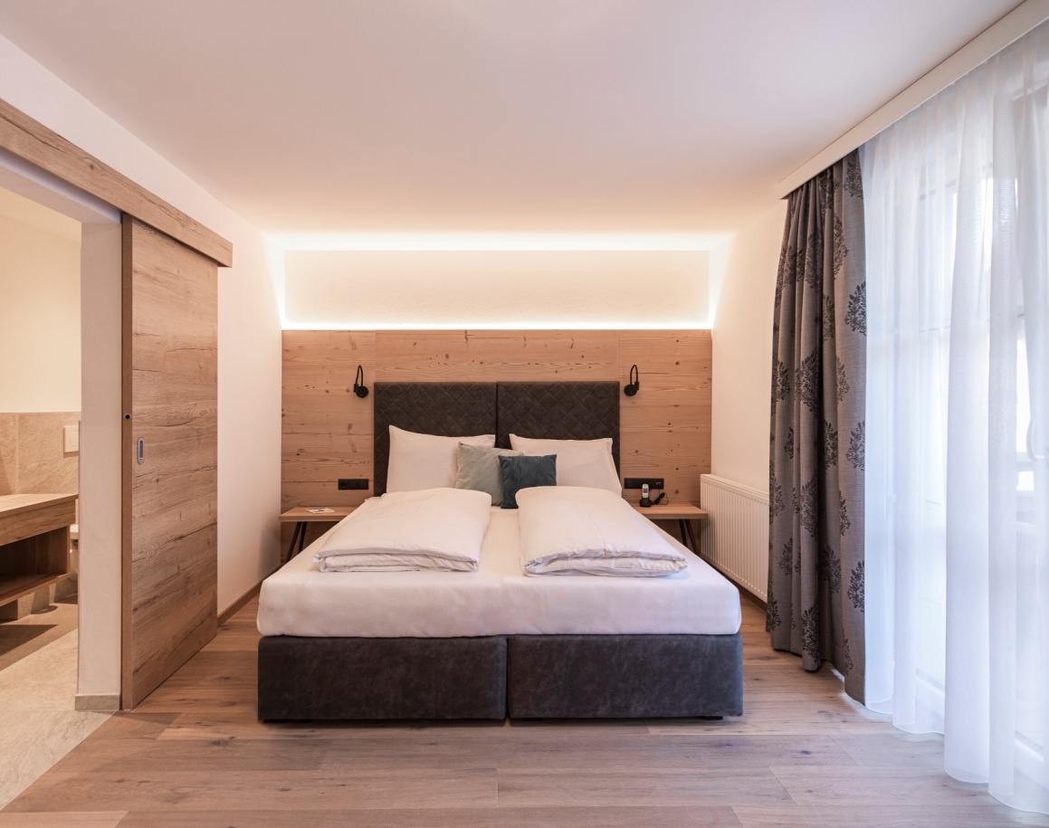 Hotelzimmer mit Doppelbett und großen Fenstern in der Emmy Lodge Flachau